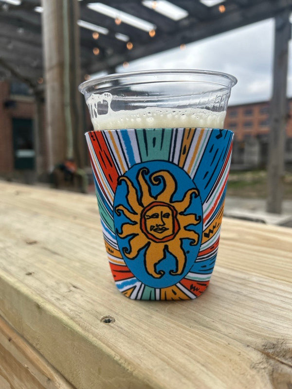 Pint sleeve featuring a starburst of colors, including blue, yellow, sea green, and orange. Features Oberon logo in blue, orange, and yellow.