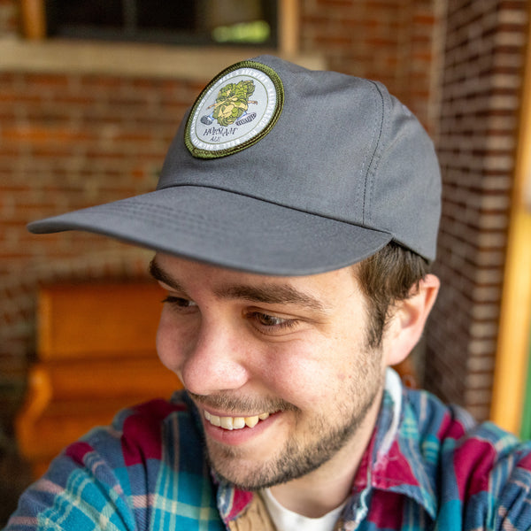 Grey flatbrim hat with circular patch featuring Hopslam logo with green border