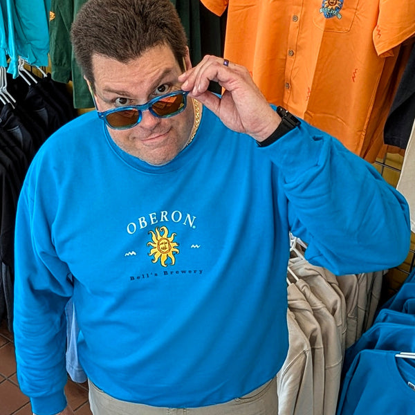 vibrant teal crewneck sweatshirt with Oberon in white lettering above a full color Oberon sun, and Bell's Brewery printed in black below sun.  Graphic is placed front and center on garment