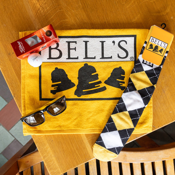Yellow golf towel, bell's black white and yellow argyle socks, black and yellow bell's sunglasses and bell's logo titleist 3 back of golf balls
