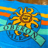 Blue bar towel with teal orange and yellow stripes and full color Oberon sun logo
