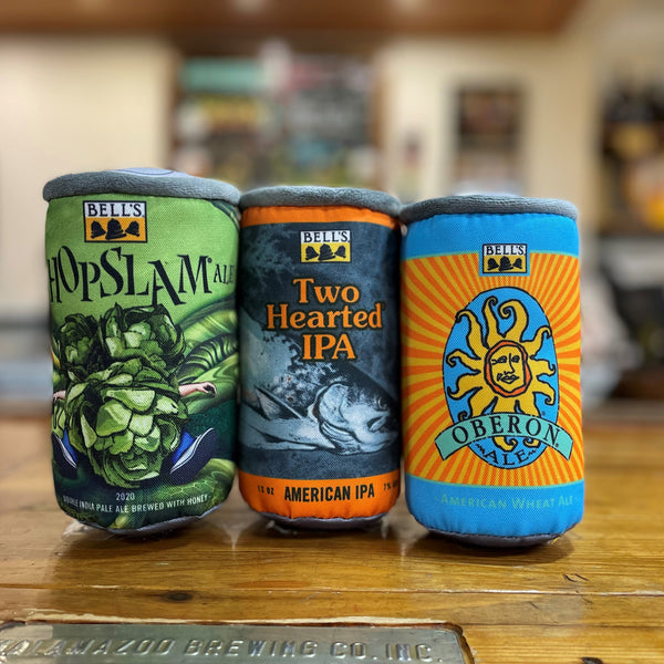Three plush can dog toys. The can on the left features Hoplsam can art. The middle can features Two Hearted IPA can art. The right can features Oberon can art.