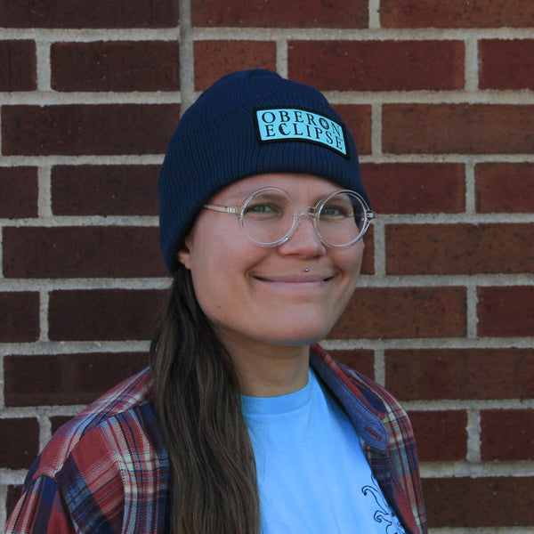 navy blue ribbed beanie with light blue rectangular patch with Oberon Eclipse text logo embroidered in black