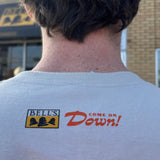 Person wearing a shirt with 'Bell's Logo and "Come on Down!' text and logo, standing in front of a building.