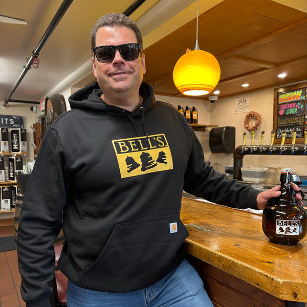 black hooded sweatshirt with front kangaroo pocket, and yellow Bell's logo printed front and center.  carhartt tag on upper right of pocket