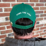 Person wearing a green cap with 'Fore the Fish' text in white above the snaps, with color Bells logo pinch tag on back left