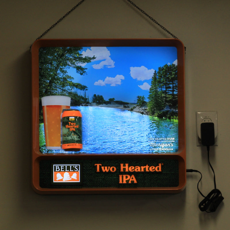 Two Hearted Ale retro-themed backlit sign with movement effects. Features a scene of the Two Hearted River in Michigan's Upper Peninsula. Features a can of Two Hearted Ale and beer in a pint glass in the lower left corner. At the bottom of the sign, features a Bell's logo with "Since 1985" in far bottom Left. And Two Hearted Ale text in orange with a white border in the bottom right.