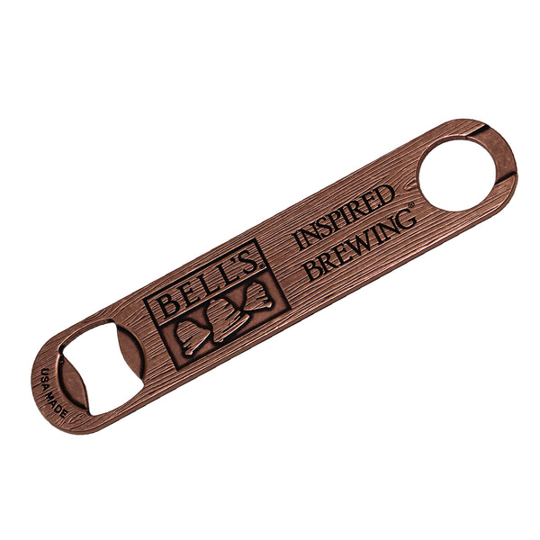 bronze metal paddle bottle opener with woodgrain texture. USA Made. Embossed Bell's logo. Embossed Inspired Brewing tagline.